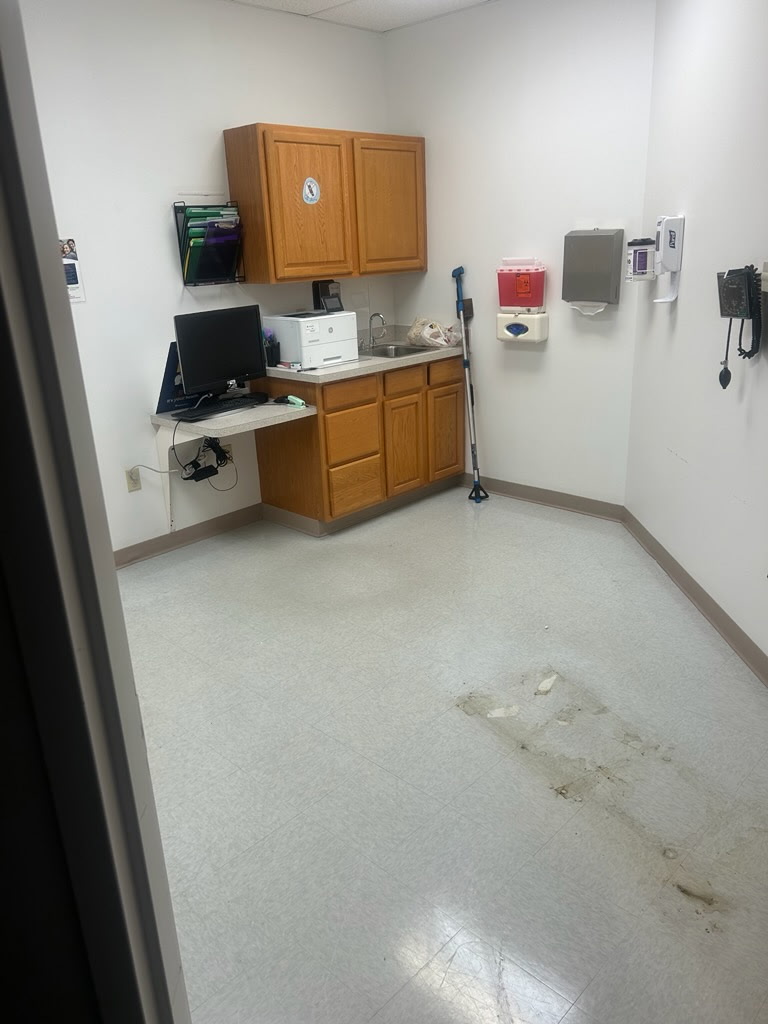 Exam room floor before cleaning, stained and scuffed