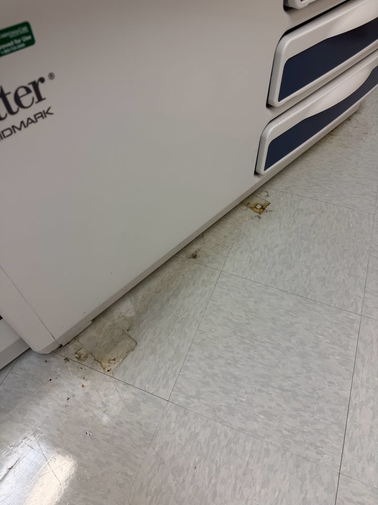 Stained floor beside an exam table before cleaning